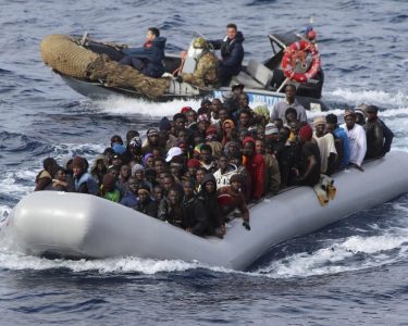 Migrants Sit In A Boat During A Rescue Operation By Italian Navy Off The Coast Of The South Of The Italian Island Of Sicily