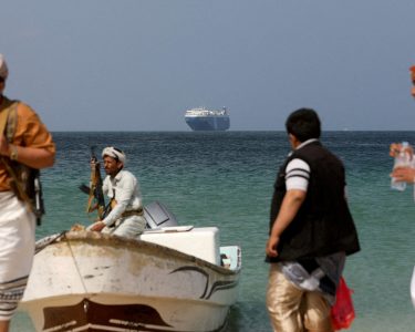 File Photo: Armed Men Stand On The Beach As The Galaxy Leader Commercial Ship, Seized By Yemen's Houthis Last Month, Is Anchored Off The Coast Of Al Salif